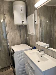 ein weißes Badezimmer mit Waschbecken und Spiegel in der Unterkunft Arctic Sea Apartments in Hammerfest