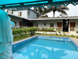 ein Swimmingpool vor einem Haus in der Unterkunft Indraprastha Cottage in Alibag