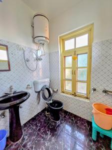 een badkamer met een wastafel en een toilet en een raam bij Sahil cottage in Chamba