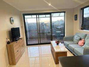 Albany Sunny Deck Retreat في أوكلاند: غرفة معيشة مع أريكة وتلفزيون