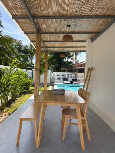 a wooden table and chairs under a wooden pergola at Pinky Bungalow Resort & Villa - SHA Extra Plus in Ko Lanta