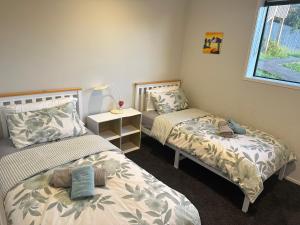 奥克兰Fairview Heights Sunny Deck Retreat的一间卧室设有两张床、一盏灯和一扇窗户。