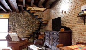 a living room with a tv and a brick wall at La Quintana de Antón in Jomezana