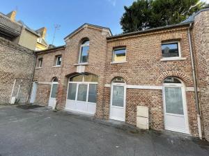a brick building with white garage doors on a street at Twilight Star Spa - Sauna & Private Cinema - Free Parking in Amiens