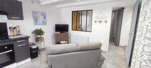 a white living room with a couch and a television at Studio Lindois in Lalinde +2 photos