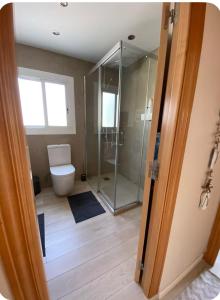 a bathroom with a toilet and a glass shower at Ocean View Sunny Beach Apartment Castelldefels in Castelldefels