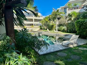 Cape Bay by AAA Rentals - Cap Malheureux في كاب مالهيريوكْسْ: مسبح في ساحة فيها كرسي ومبنى