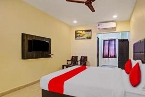 Schlafzimmer mit einem Bett mit roten Kissen und einem TV in der Unterkunft Super Hotel O Lakshmi Royal Inn in Warangal