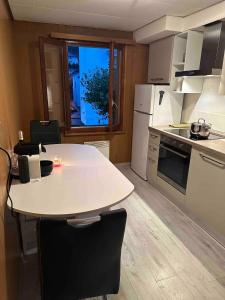 Una cocina con una mesa blanca con sillas y una ventana. en Faido Apartment, en Faido
