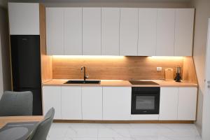 a kitchen with white cabinets and a sink at The Minimalist Escape in Kamëz