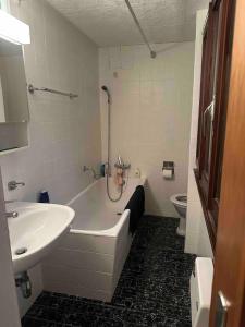Un baño con bañera, lavabo e inodoro. en Faido Apartment, en Faido