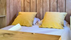 uma cama com dois travesseiros amarelos e uma parede de madeira em Cabaña Le Sapin em Osséja