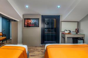 two beds in a room with orange sheets at AirGate Airport Hotel in Arnavutköy