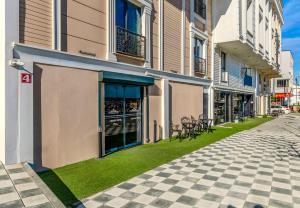 ArnavutköyにあるAirGate Airport Hotelの歩道の横の芝生の上に椅子が置かれた建物