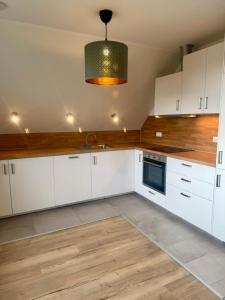 Ferienwohnung Lütte Koje beim Hinrichs Gasthof في Tümlauer Koog: مطبخ فيه دواليب بيضاء و قلادة خفيفة