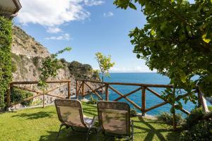 two chairs sitting in the grass near the ocean at Villa Elisa by My Villa Collection in Conca dei Marini