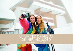 two women taking a picture in front of a house at Pohorje Village Wellbeing Resort - Wellness & Spa Hotel Bolfenk in Pohorje