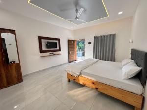 a bedroom with a bed and a tv on the wall at Indraprastha Cottage in Alibaug