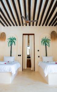 zwei Betten in einem Zimmer mit Palmen an den Wänden in der Unterkunft Tulia House Lamu in Lamu + 101 Fotos