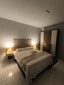 a bedroom with a large bed with two lamps at Brisa do Sul in Umuarama
