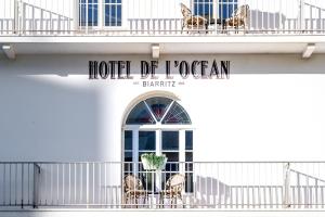 a hotel de jocgan sign on a building with chairs at Hotel de l'Océan et restaurant - Coeur de ville in Biarritz