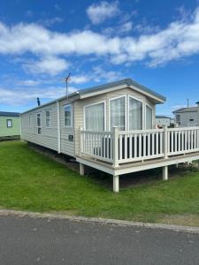 a mobile home with a porch on the grass at 16 orchid meadows in Ashington
