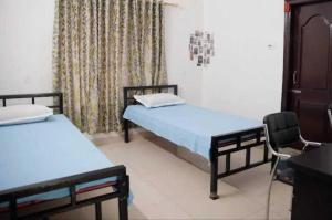 ein Zimmer mit 2 Betten und einem Stuhl darin in der Unterkunft SPOT ON Sanskrit Guest House in Dispur