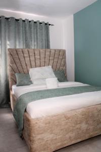 een slaapkamer met een groot bed met een houten hoofdeinde bij Willary Heights Apartment in Bungoma