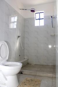 een witte badkamer met toilet en douche bij Willary Heights Apartment in Bungoma