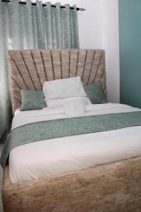een slaapkamer met een groot bed met een houten hoofdeinde bij Willary Heights Apartment in Bungoma
