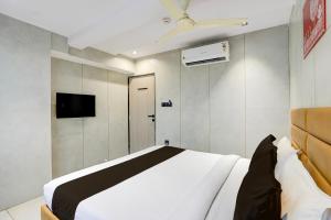 una camera da letto con un letto bianco e una tv di Hotel O by OYO Olive7 a Surat
