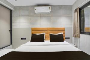 una camera da letto con un letto grande con cuscini neri di Hotel O by OYO Olive7 a Surat Altre 21 foto