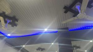 Un ventilador de techo y luces azules en una habitación. en Hotel O Shree Paying Guest House, en Rāmnagar