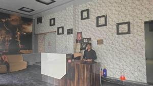 un hombre sentado en un mostrador en una habitación en Hotel O Shree Paying Guest House, en Rāmnagar