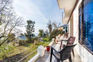 a balcony with two chairs and a large window at Holistic House in Dharamshala
