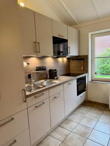 a kitchen with white cabinets and a sink and a window at Cozy Beach Home in De Haan +8 photos