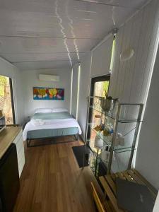 Un dormitorio con una cama en una habitación con suelo de madera. en Hill Creek Tiny House 5 by Tiny Away, en Perwillowen 8 fotos más