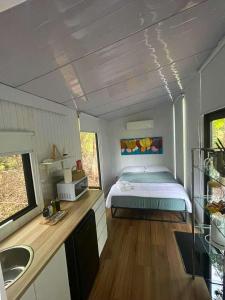 Un dormitorio con una cama y un lavabo en una habitación. en Hill Creek Tiny House 5 by Tiny Away, en Perwillowen
