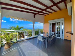 a dining room with a table and chairs on a balcony at Villa NKJ'S in Deshaies