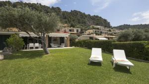 two white chairs sitting on the grass in a yard at Villa Sand and Sea in Pelekas
