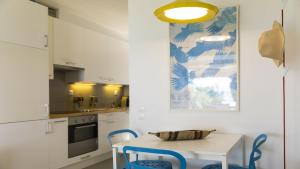 a kitchen with a white table and blue chairs at Villa Sand and Sea in Pelekas