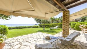 un patio con sedie, un tavolo e un ombrellone di Villa Marina a Pelekas