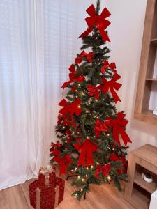 a christmas tree with red bows and a present at La Casa di Ary in Cisterna di Latina