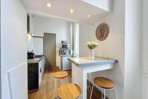 eine Küche mit einer Theke und 2 Hockern in der Unterkunft Studio élégant pour 4 personnes, à quelques pas de la Croisette in Cannes