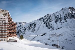 Appartement Ski, Au Pied Des Pistes في لا مونجي: جبل مغطى بالثلج مع مبنى في المقدمة