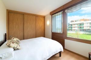 a bedroom with a white bed and a large window at Apartamento Mirador Playa de Barro in Barro de Llanes