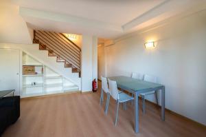 a dining room with a table and chairs and a staircase at Apartamento Mirador Playa de Barro in Barro de Llanes