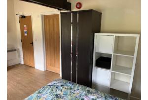 ein Schlafzimmer mit einem schwarzen Schrank und einem Bett in der Unterkunft Halfway Inn in Morden