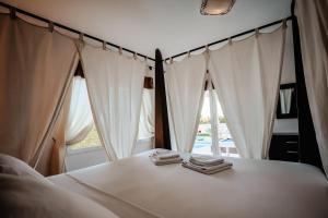 Schlafzimmer mit weißen Vorhängen und einem Bett mit Handtüchern in der Unterkunft Silversol in Jávea