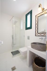 een badkamer met een wastafel, een toilet en een spiegel bij Villa Ilenia in Skála Kefalonias